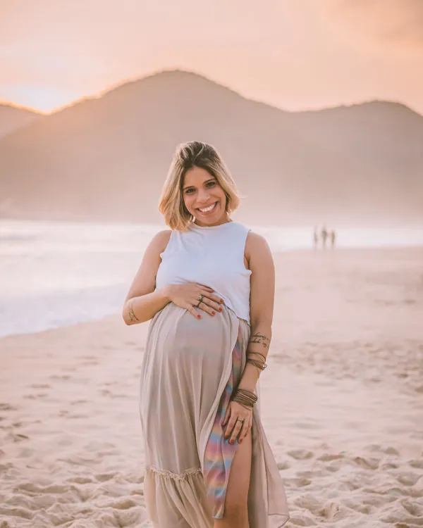 Gestante sorrindo com as mãos sobre a barriga